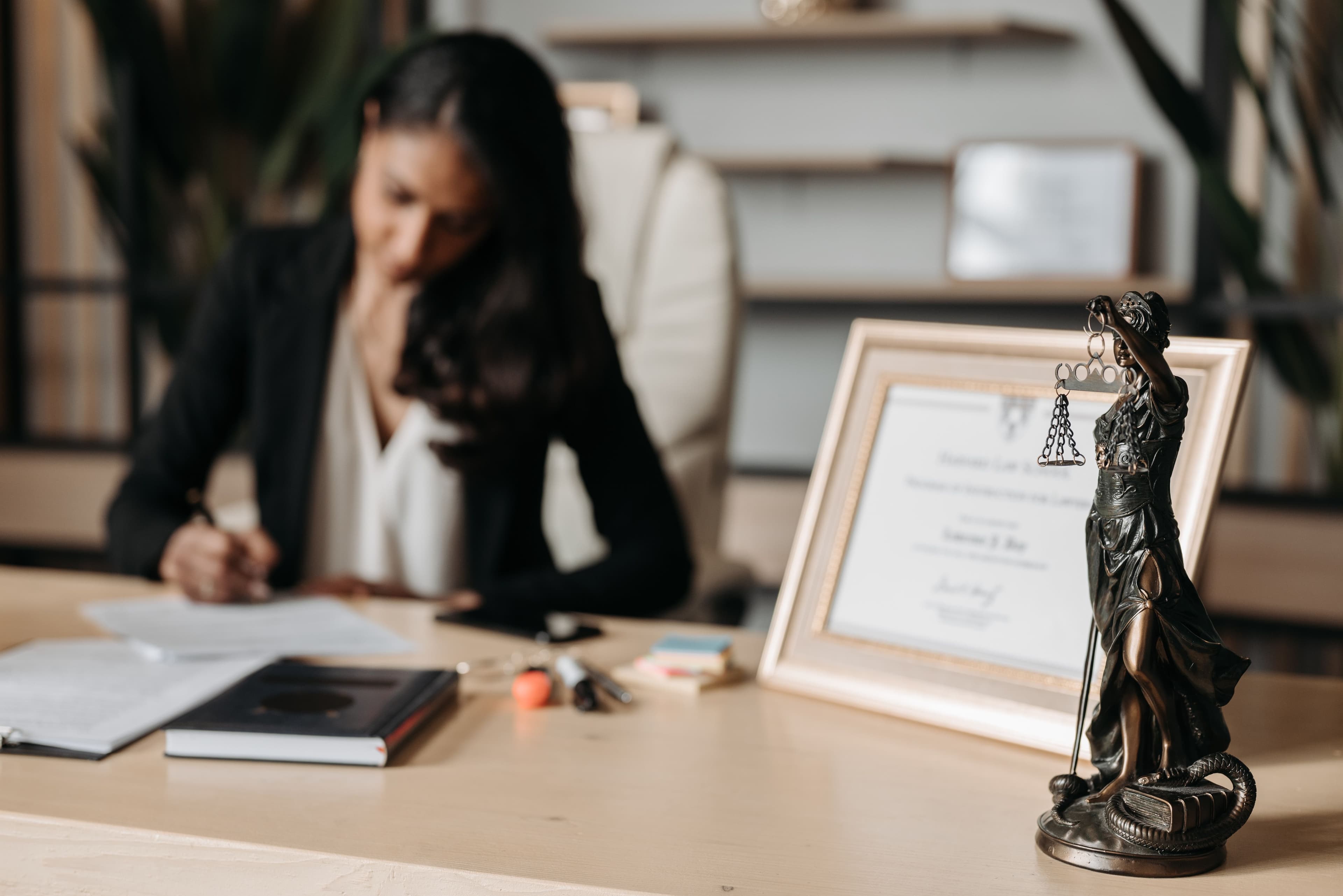 Attorney working at a desk with legal documents and a Lady Justice statue