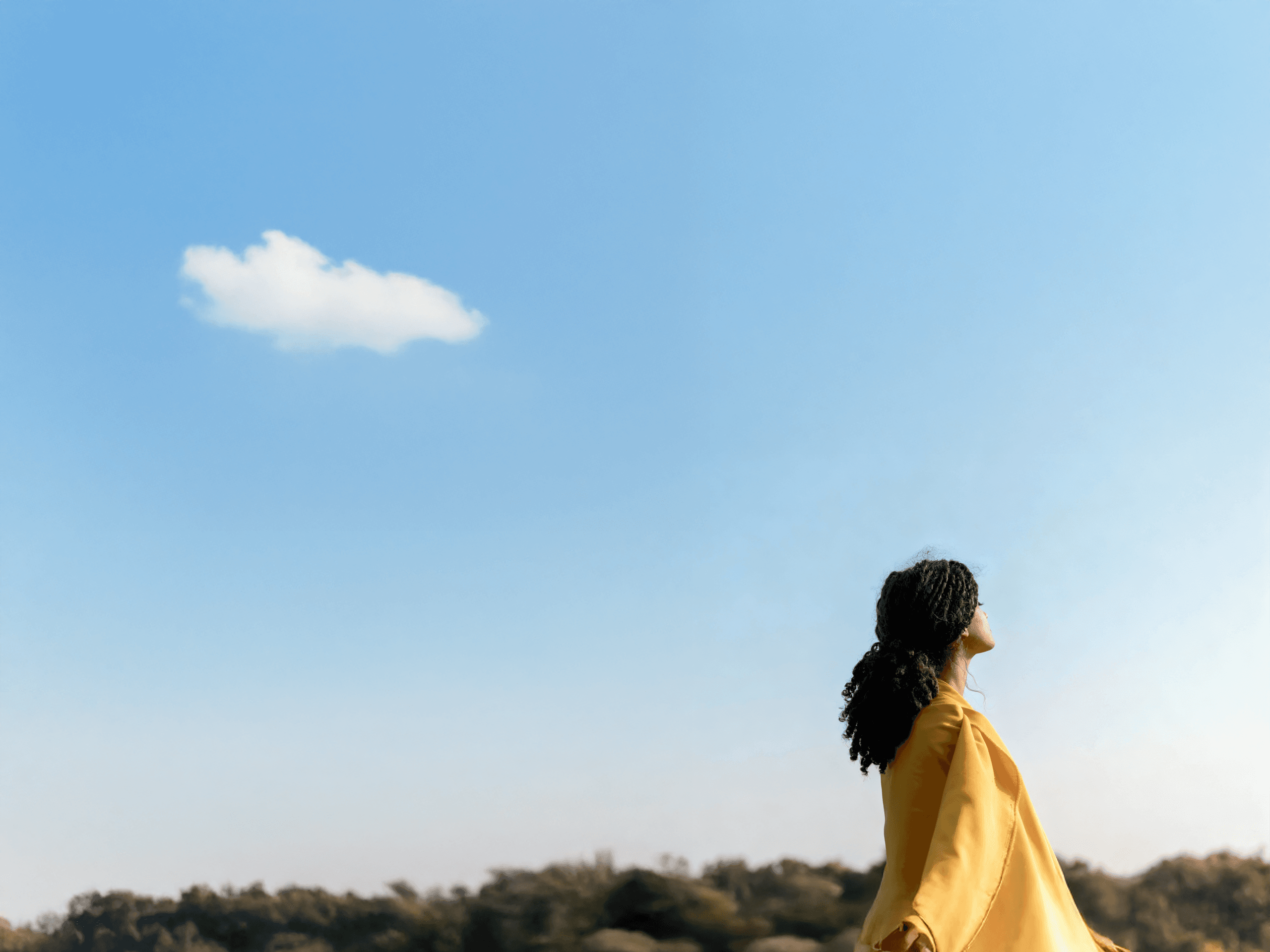 Woman in yellow jacket looking up at the sky